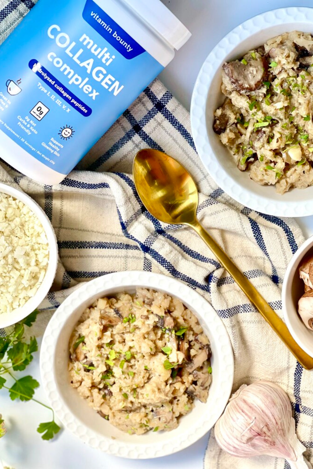 Cauliflower Risotto made with Vitamin Bounty Collagen Complex pictured on a baking cloth with gold spoon, surrounded by ingredients (garlic, cauliflower)