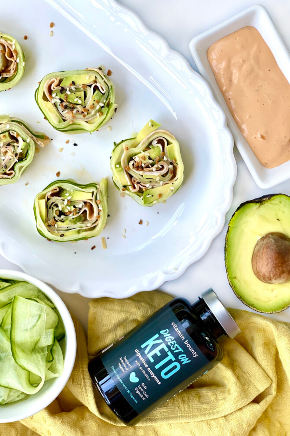 Cucumber Roll Ups pictued on a golden cloth with avocado and spicy mayo dressing