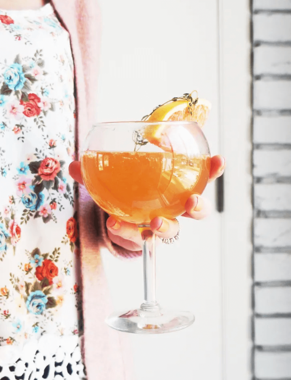 woman holding a mimosa topped with an orange slice