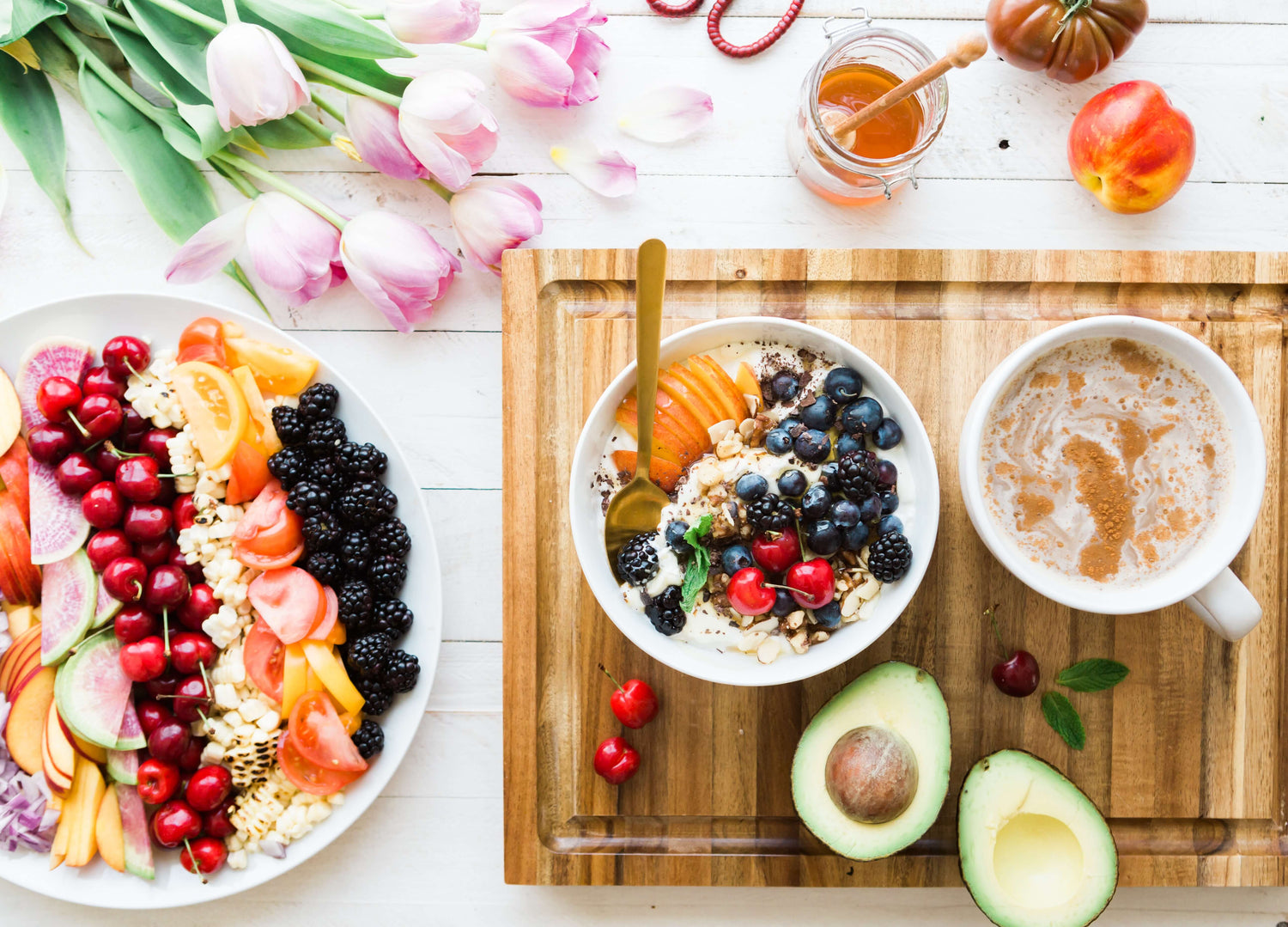 fruit on a wooden cutting board with a latte and smoothie bowl