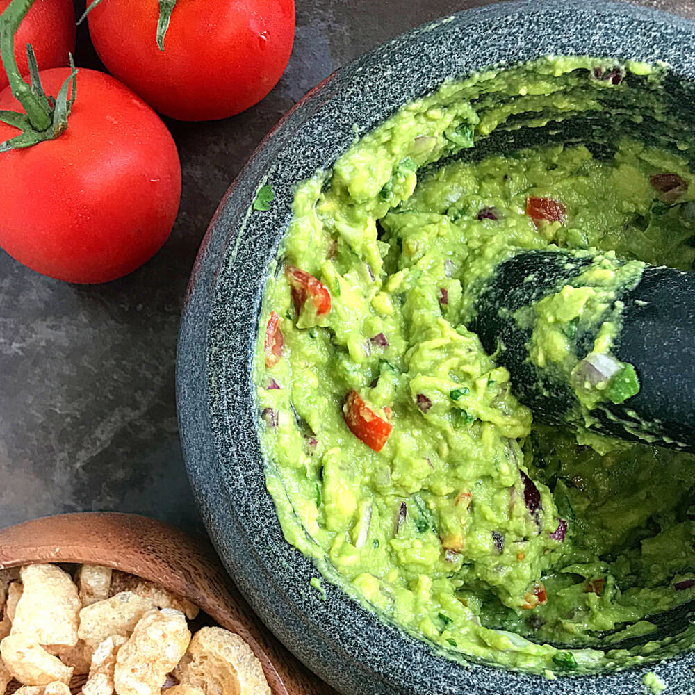 Keto-Friendly Guacamole in stone bowl with tomatoes and garlic