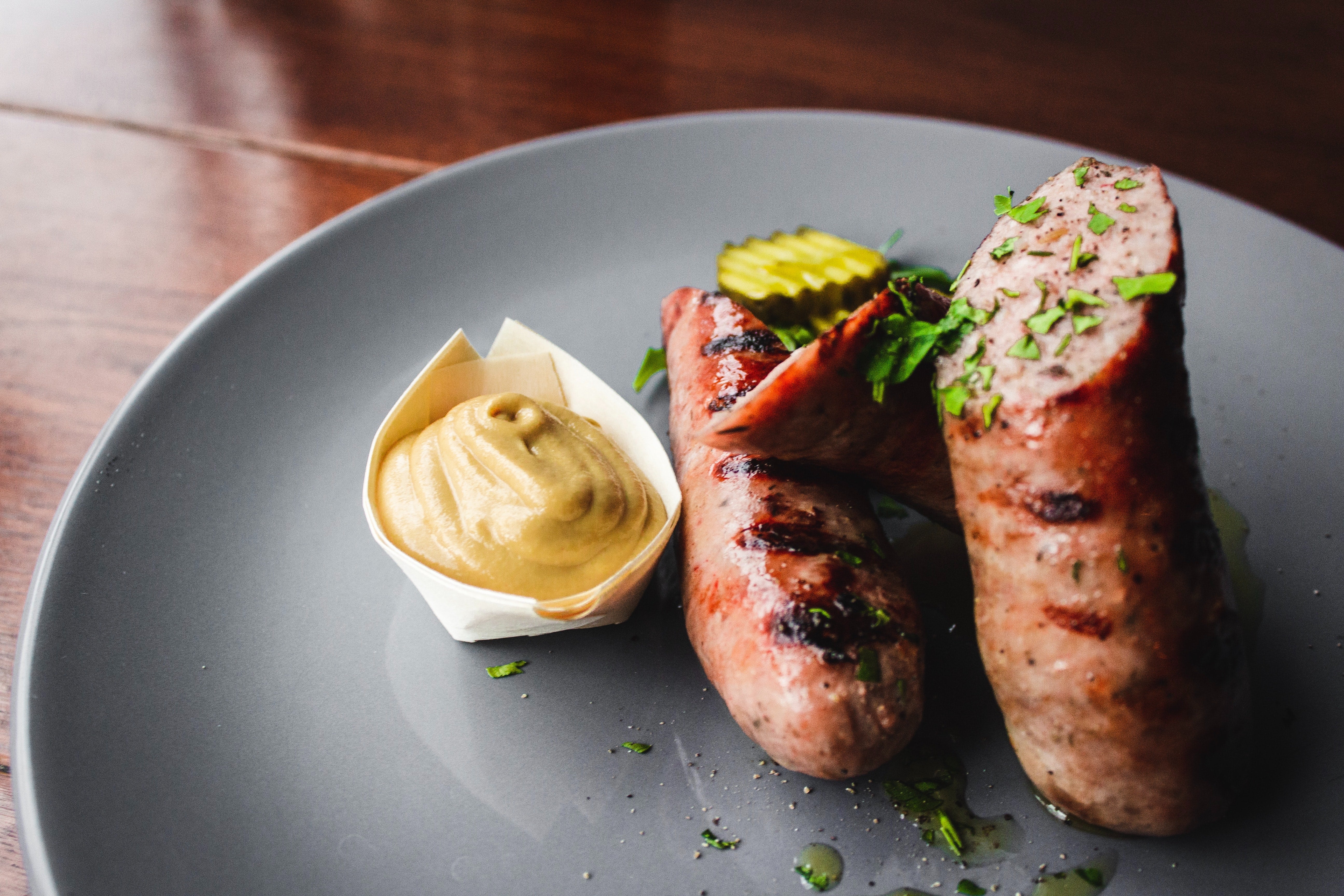 Pork sausage on blue plate with side of mustard 