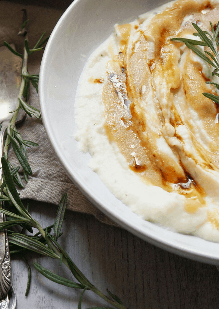 Cauliflower Mash in a white bowl topped with rosemary