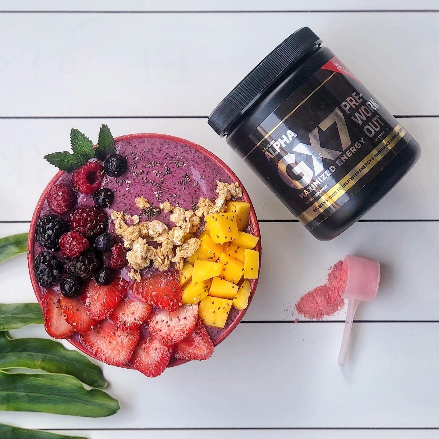 Purple smoothie bowl, with GX7 pre workout beside it, topped with assorted fruit 