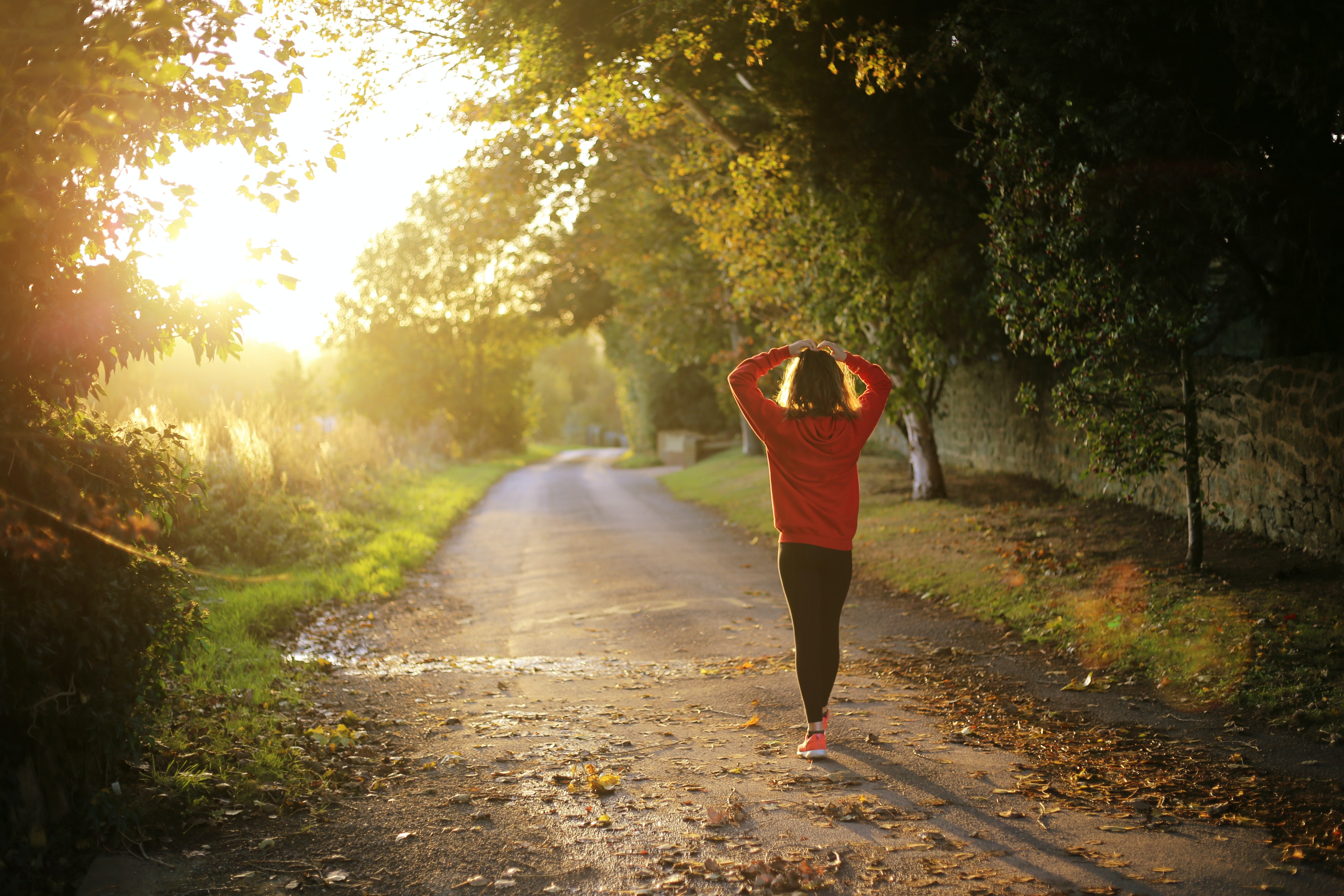 Woman stopping on a sun lit path, during her morning run